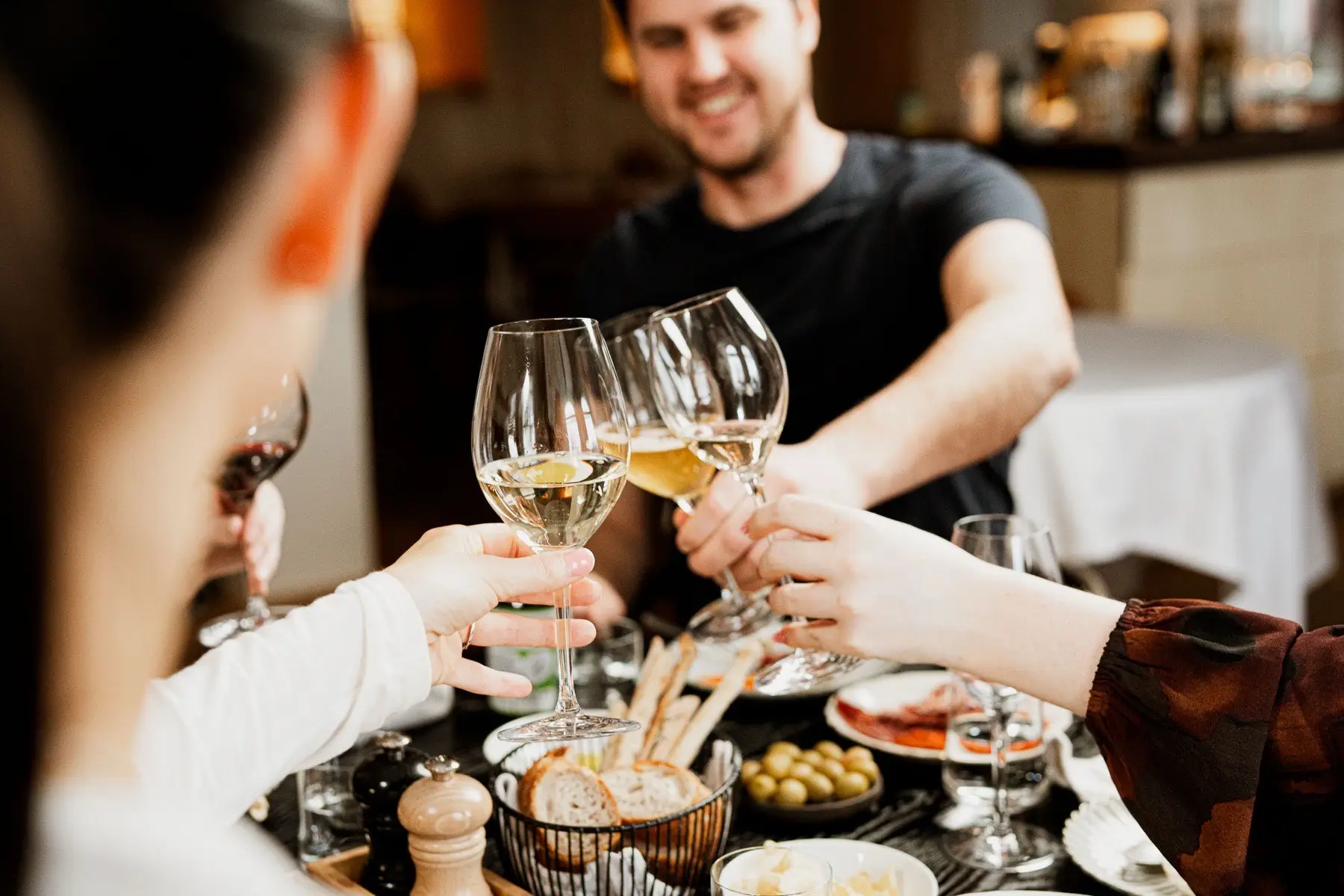Gäster skålar i vitt vin vid ett dukat bord på Bröd & Vin.